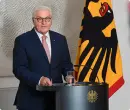 Photo of German President Frank-Walter Steinmeier next to a German Federation flag.