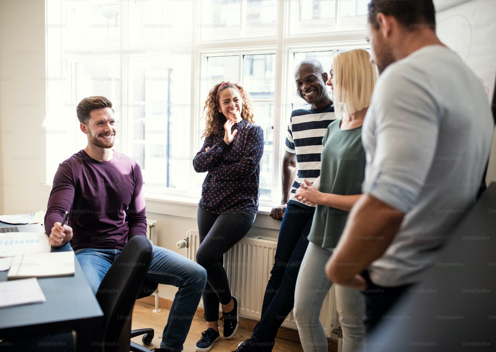 Photo of professionals smiling around documents in an office, showcasing collaboration.