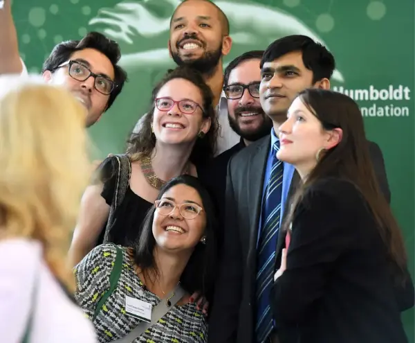 Hero image of American Friends of AvH homepage featuring a diverse group of professionals at a networking event.